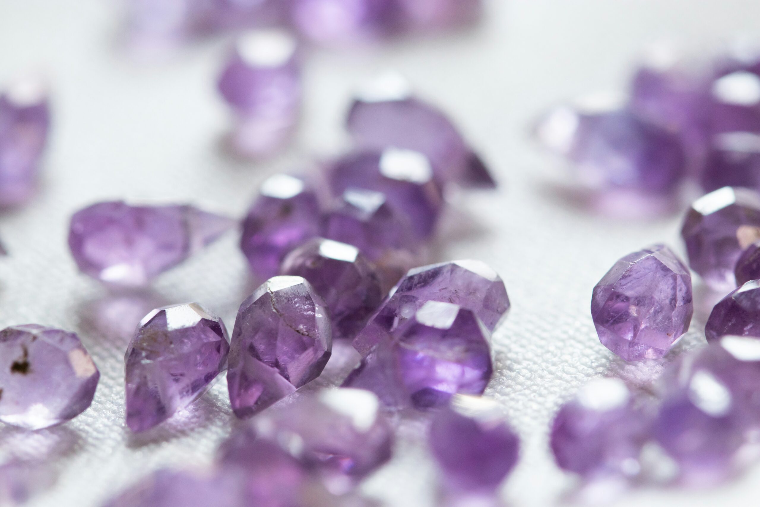 Purple gemstones in closeup with a white background.